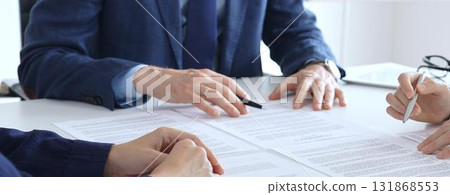 Businessman or lawyer pointing into contract papers with black pan and discussing documents with colleagues in a bright office. Business people concept 131868553