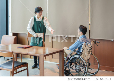 咖啡館工作人員引導一位坐輪椅的男子 131869805