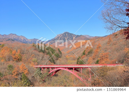 Higashizawa Bridge and Yatsugatake covered in autumn leaves 131869964