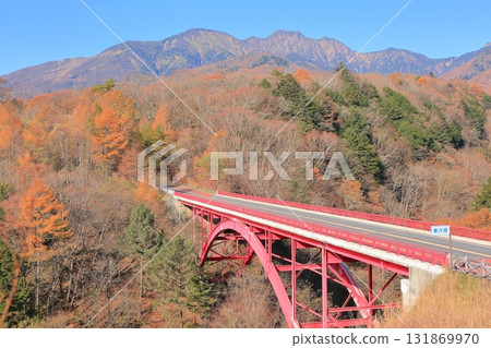 Higashizawa Bridge and Yatsugatake covered in autumn leaves 131869970
