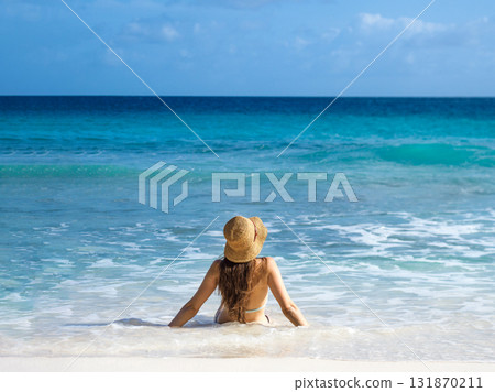 Cute woman sitting on stunning white sand beach 131870211