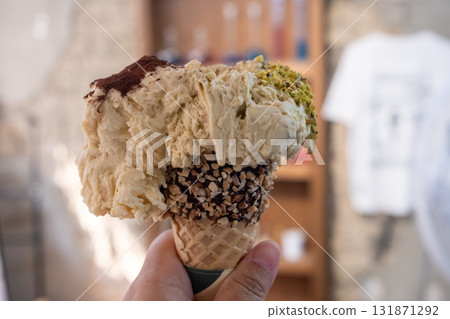 Hand holding Pistachio and Tiramisu Gelato, Ice-cream with waffle cone 131871292