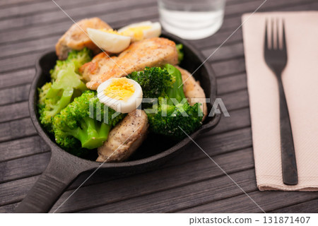 chicken breast with broccoli and quail eggs in small cast iron skillet 131871407