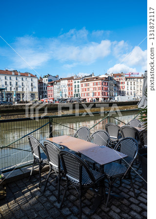 法國巴斯克地區巴約訥河畔餐廳前排列整齊的餐桌和歷史建築的街景 法國巴斯克地區巴約訥河畔餐廳前排列整齊的餐桌和歷史建築的街景 131872117