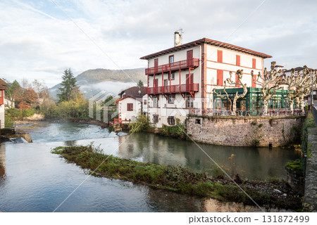 Historic buildings and trees along the river in the morning mist in Saint-Jean-Pied-de-Port, Basque Country, France 131872499