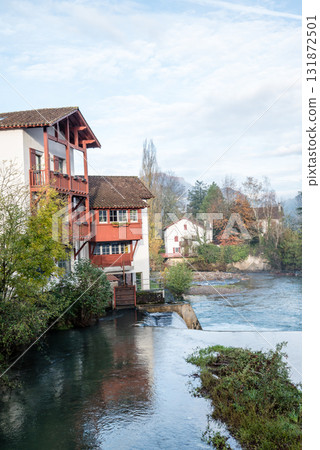 Historic buildings and trees along the river in the morning mist in Saint-Jean-Pied-de-Port, Basque Country, France 131872501