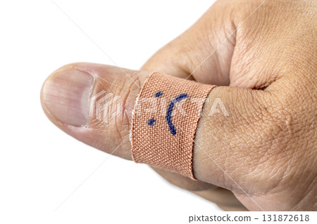 Thumb wrapped in bandage with sad face drawn on it, conveying sense of injury or discomfort. close up image highlights texture of skin and bandage Thumb wrapped in bandage with sad face drawn on it, conveying sense of injury or discomfort. close up image highlights texture of skin and bandage 131872618
