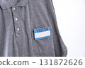Gray shirt with visitor badge on pocket, featuring blue and white design. shirt is casual polo style, emphasizing professional yet relaxed appearance 131872626