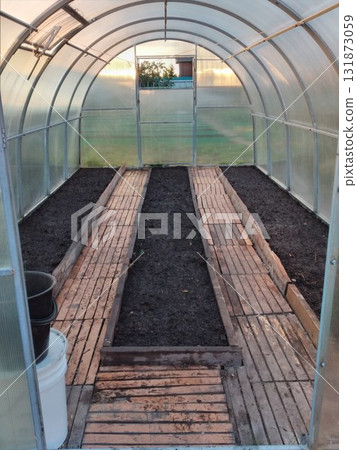 An empty greenhouse with prepared soil after harvesting. 131873059