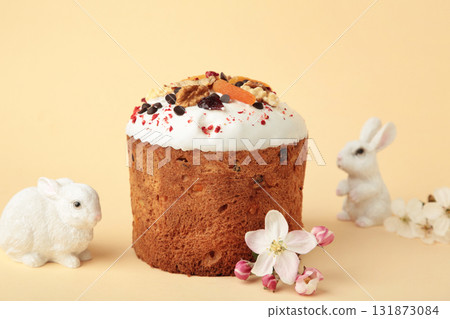Traditional easter cakes with colorful sprinkles, bunny figurine, and spring flowers on beige background. Traditional easter cakes with colorful sprinkles, bunny figurine, and spring flowers on beige background. 131873084