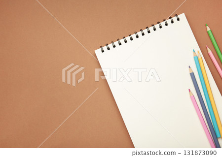 Sketchbook and colored pencils on brown background 131873090