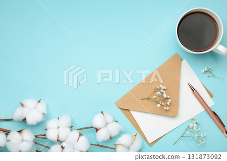 Composition with craft envelope and cotton branch on blue background Composition with craft envelope and cotton branch on blue background 131873092