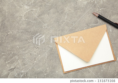 Craft envelope with paper card and pen on grey concrete background. Space for text Craft envelope with paper card and pen on grey concrete background. Space for text 131873108