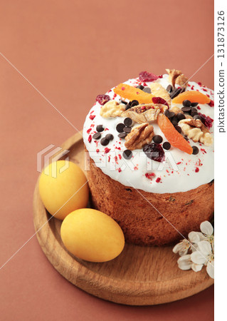 Traditional easter cakes with colorful sprinkles, with eggs and spring flowers on brown background. 131873126