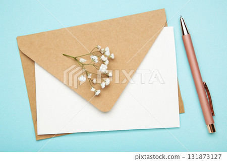 Craft envelope with paper card, pen and white gypsophila flowers on pastel blue background. Space for text Craft envelope with paper card, pen and white gypsophila flowers on pastel blue background. Space for text 131873127