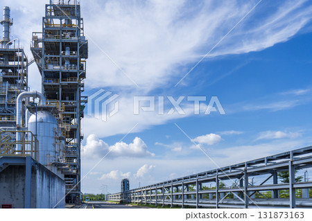 Large industrial plant with a tall tower and a long pipe 131873163