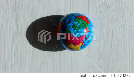 A top view of the North Pole on a colored globe that casts a textured shadow on a wooden surface. Conceptual photo illustrating different times of day on planet Earth A top view of the North Pole on a colored globe that casts a textured shadow on a wooden surface. Conceptual photo illustrating different times of day on planet Earth 131873222