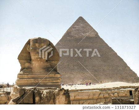 Large pyramid is in the background of a picture of a statue 131873327