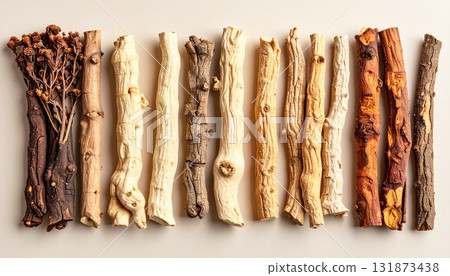 A neatly arranged flat lay of dried adaptogenic roots and herbs such as ashwagandha and rhodiola, displayed in small wooden bowls on a neutral background, symbolizing natural wellness and balance 131873438
