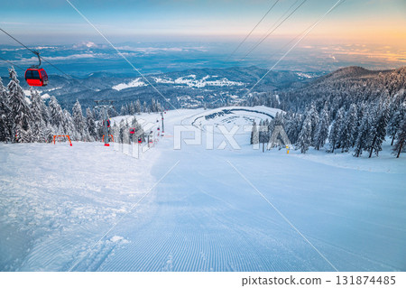 Ski gondolas above the groomed ski slope at sunrise Ski gondolas above the groomed ski slope at sunrise 131874485