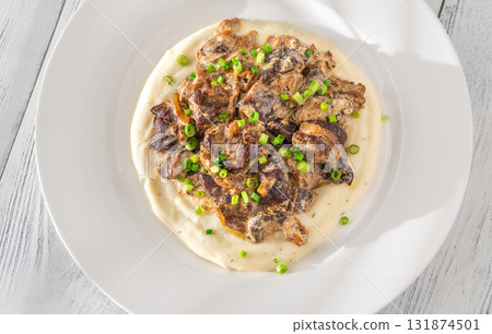 Braised meat and mushroom topping over creamy mashed potato served on white plate 131874501