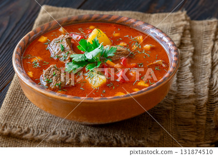 Rustic clay bowl filled with traditional Hungarian Bogracs stew on wooden table Rustic clay bowl filled with traditional Hungarian Bogracs stew on wooden table 131874510