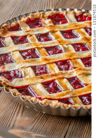 Freshly baked lattice-top cherry pie resting beautifully on rustic wooden surface 131874518