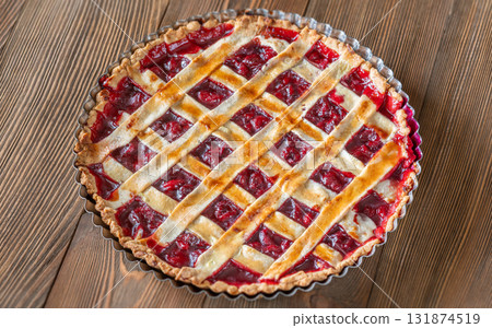 Freshly baked lattice-top cherry pie resting beautifully on rustic wooden surface 131874519
