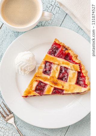Cherry pie slice with melting ice cream and coffee on white plate 131874527