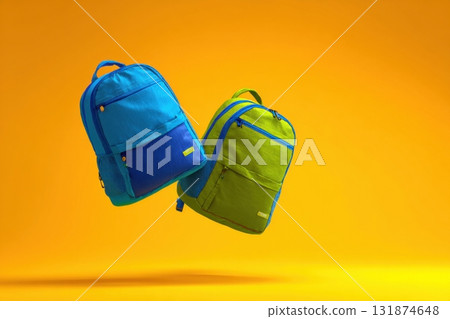 Two vibrant neon green and blue backpacks floating in the air isolated on yellow background. Colorful school bags are suspending mid-air. Dynamic movement composition. product presentation, playtime 131874648