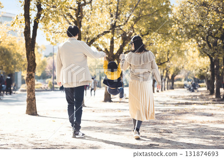 一個親密的家庭手牽手沿著秋天公園裡綠樹成蔭的小路散步 一個親密的家庭手牽手沿著秋天公園裡綠樹成蔭的小路散步 131874693