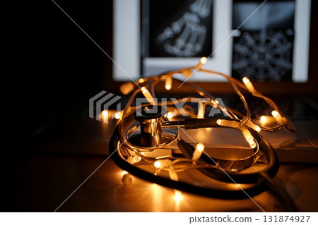 Stethoscope decorated with colorful festive lights lying on a chest x-ray, holiday healthcare concept for doctors and nurses 131874927