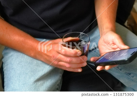 Man holding phone and glass of drink Man holding phone and glass of drink 131875300