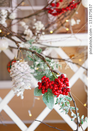 Christmas decor red berries with green leaves on shining lights background and pine cones 131875637