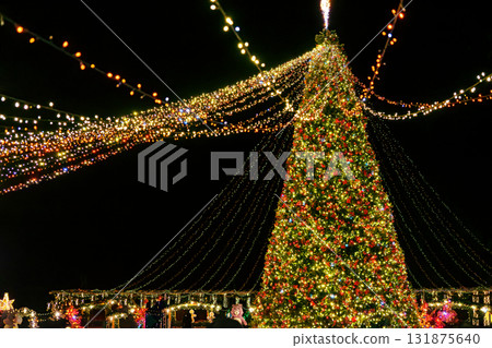 Giant Christmas tree with festive lights and glowing decorations at night fair, holiday celebration Giant Christmas tree with festive lights and glowing decorations at night fair, holiday celebration 131875640
