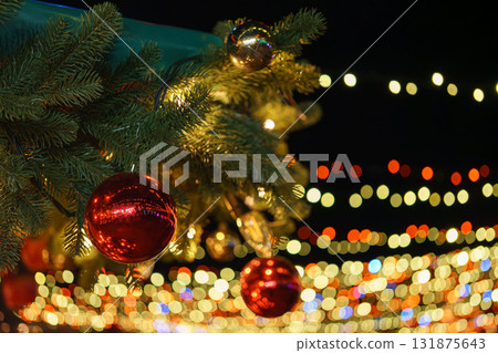 Christmas tree branch decorated with shiny red balls on glowing festive holiday lights background 131875643