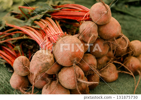 Fresh red beets with stems tied together in bunches at a market stall, symbolizing organic farming 131875730