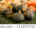 Fresh green pumpkins stacked in a pile at a market stall, symbolizing seasonal harvest, organic 131875732