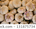 Fresh garlic bulbs arranged in bulk at a market stall, representing organic farming, natural 131875734