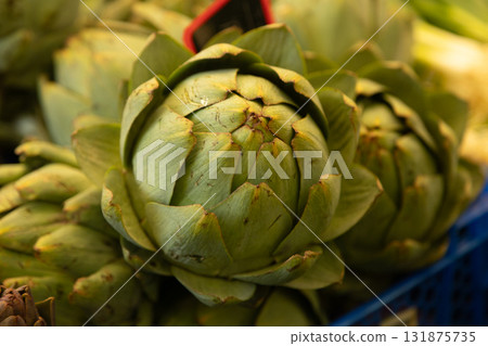 Fresh green artichoke photographed closeup at a market stall, symbolizing organic farming, healthy Fresh green artichoke photographed closeup at a market stall, symbolizing organic farming, healthy 131875735