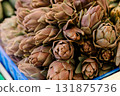 Fresh artichokes arranged in a pile at a market stall, symbolizing organic farming, seasonal harvest 131875736