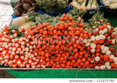 Fresh red and white radishes arranged in large bunches at a farmer market stall, symbolizing organic 131875740