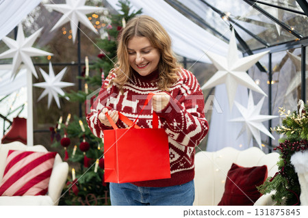 Middle age Caucasian woman smiling confident holding Christmas gift bag at home. Winter time and holidays. Celebration banner, big sale concept Middle age Caucasian woman smiling confident holding Christmas gift bag at home. Winter time and holidays. Celebration banner, big sale concept 131875845