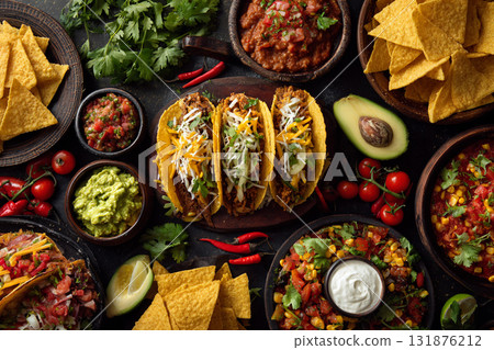 A vibrant overhead flat lay of Mexican and Southwestern dips and ingredients, including salsa, guacamole, black beans, and tortilla chips on a turquoise wooden surface. 131876212