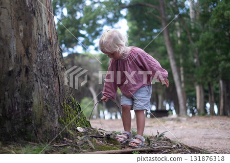 Blonde girl found a mushroom in the forest and pokes it with a stick Blonde girl found a mushroom in the forest and pokes it with a stick 131876318
