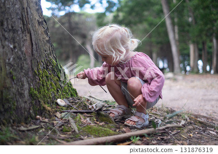 Blonde girl found a mushroom in the forest and pokes it with a stick Blonde girl found a mushroom in the forest and pokes it with a stick 131876319