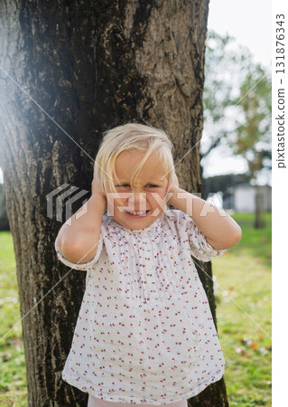 Little 4-year-old girl covering her ears from loud noise 131876343