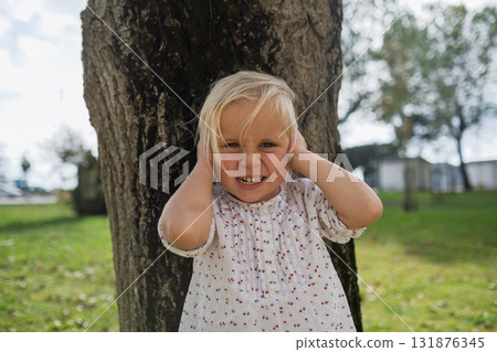 Little 4-year-old girl covering her ears from loud noise 131876345