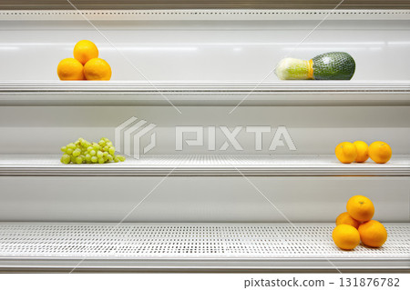 Sparse fruit display on minimal Japanese market shelf with oranges grapes and wrapped melon clean white background modern retail fresh produce simple arrangement calm atmosphere 131876782