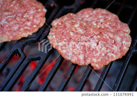 Raw burger patties on grill over hot coals Raw burger patties on grill over hot coals 131876991